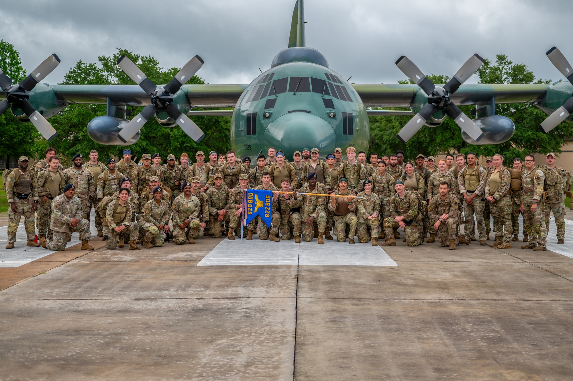 Group of individuals pose in front of a plane.