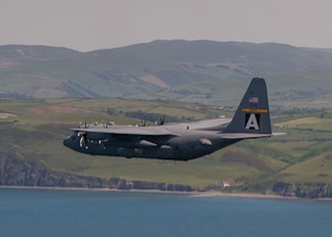 A U.S. Air Force C-130H Hercules flies over water in the United Kingdom