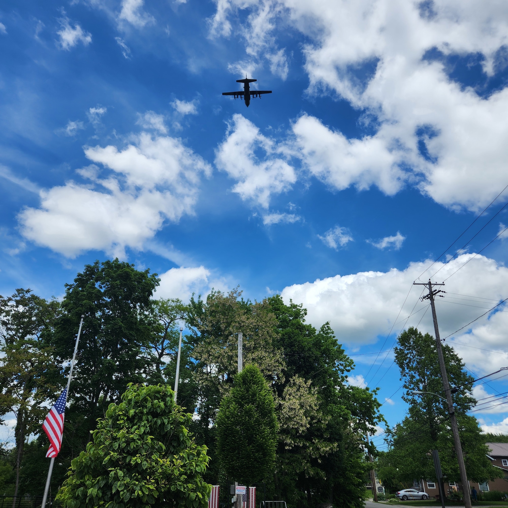 A C-130H Hercules aircraft, assigned to the 910th Airlift Wing at nearby Youngstown Air Reserve Station, Ohio, flies over the Veteran’s Memorial on the Triangle in Cortland, Ohio, to mark the start of the city’s Memorial Day ceremony on May 26, 2025.