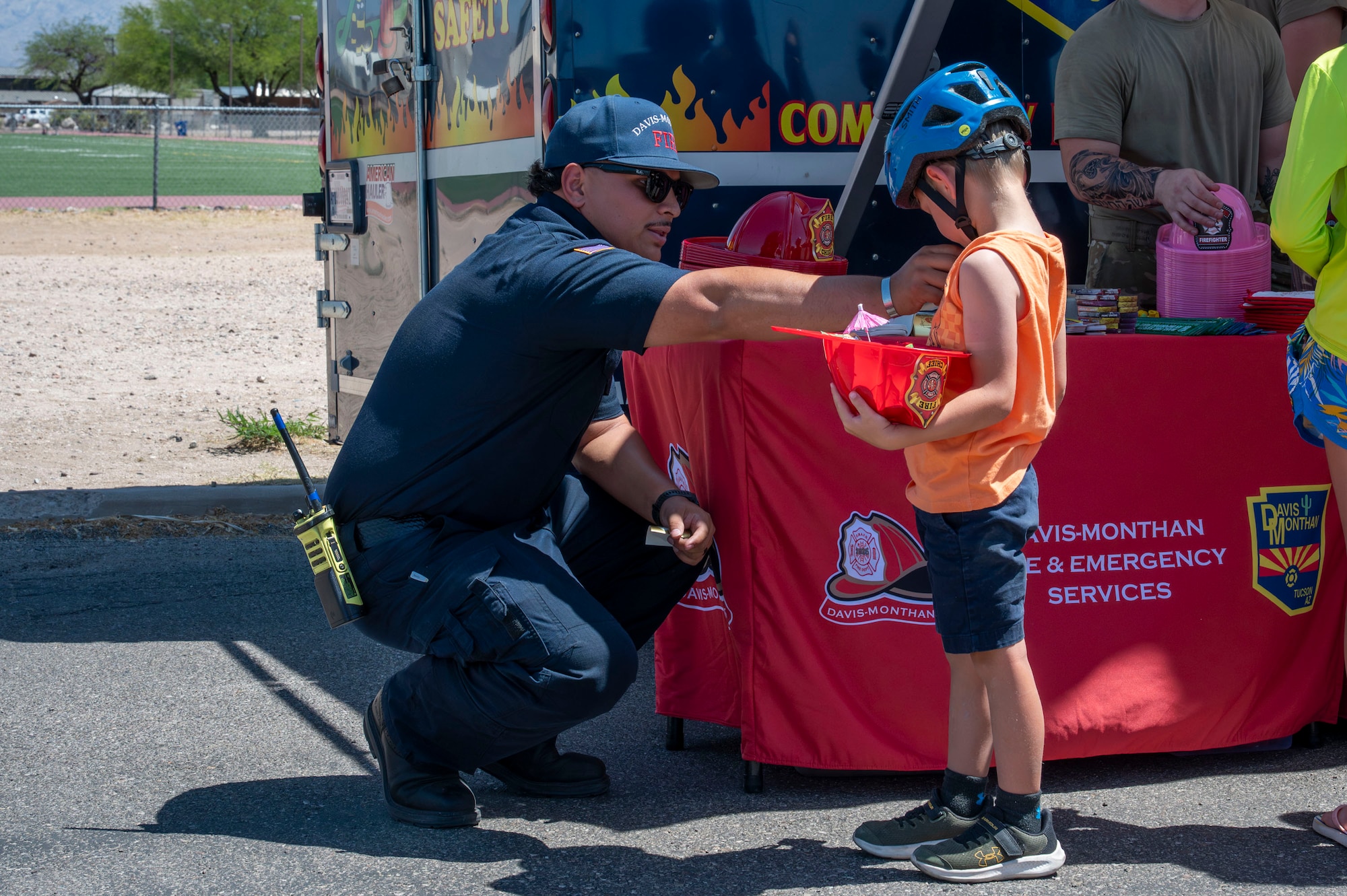 Capt. Joseph Vargas, 355th Civil Engineer Squadron firefighter, places a badge sticker on a child attending the Health Fair at Davis-Monthan Air Force Base, Arizona, May 28, 2025. The 355th Medical Group’s Health Fair combined educational booths, wellness activities and health awareness efforts to empower attendees in sustaining peak performance and overall force resilience. (U.S. Air Force photo by Airman Samantha Melecio)