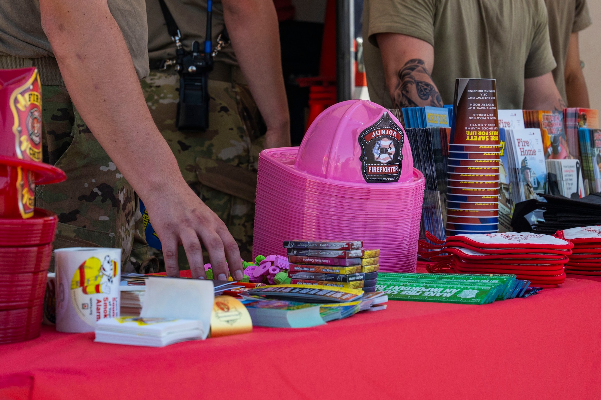 A U.S. Air Force firefighter from the 355th Civil Engineer Squadron reaches for a pencil to hand out during the Health Fair at Davis-Monthan Air Force Base, Arizona, May 28, 2025. The 355th Medical Group hosted the fair to promote comprehensive wellness and mission readiness across the installation. (U.S. Air Force photo by Airman Samantha Melecio)
