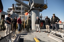 Master of Training Support Vessel (TSV) 5 Vindicator Mike Schoeller, right with hand raised, discusses the ship’s capabilities and TSV operations with Vice Adm. John Gumbleton, commander, Task Force 80 and deputy commander, U.S. Fleet Forces Command, fourth from left, during a fleet visit to Vindicator (TSV 5), assigned to Training Support Vessel Squadron (TSVRON) 4, at Naval Amphibious Base Little Creek, Va., Feb. 24, 2025.