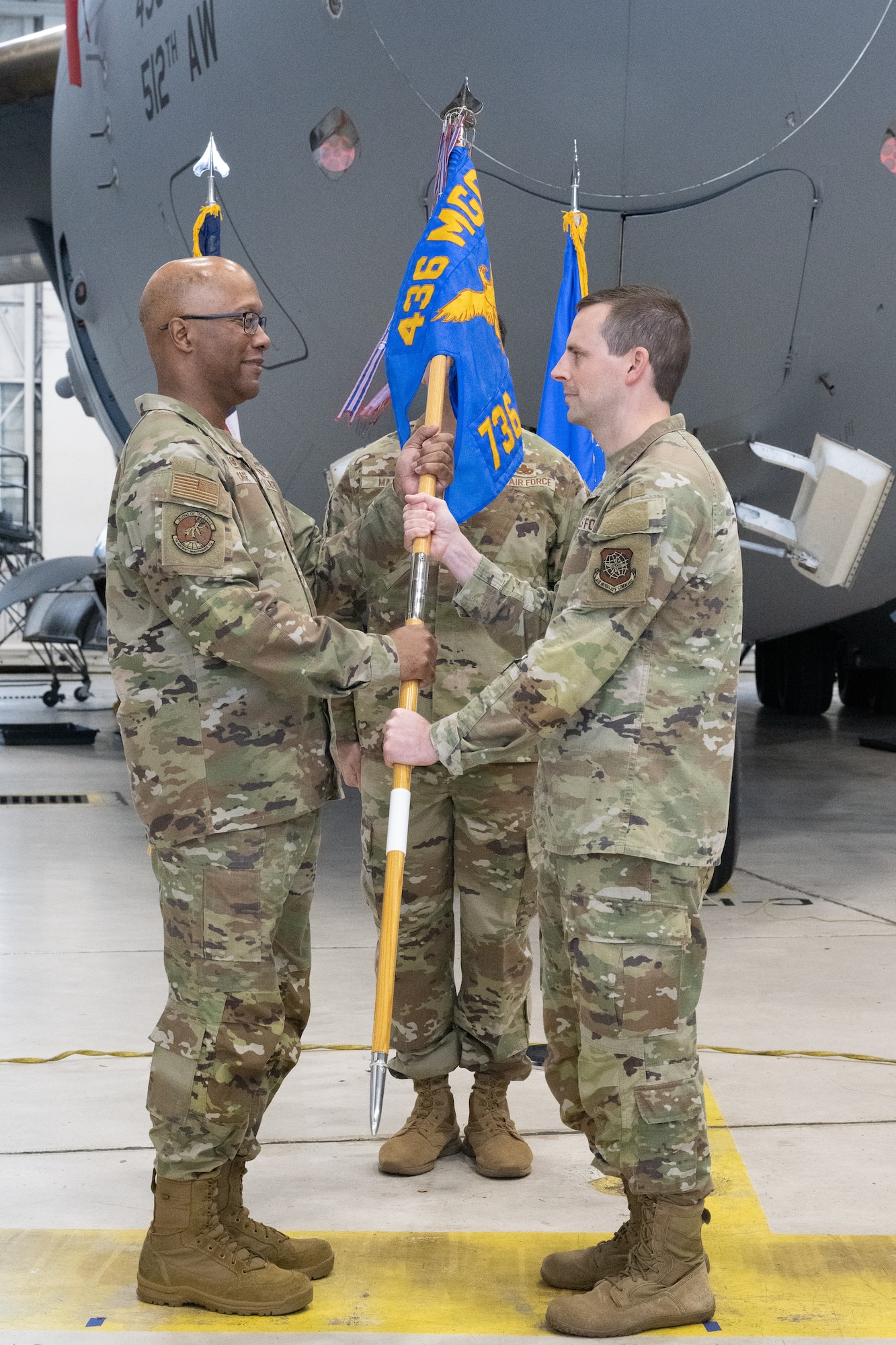 U.S. Air Force Maj. Shane Connolly, right, outgoing 736th Aircraft Maintenance Squadron commander, passes the guidon to Col. Ernest Cage, 436th Maintenance Group commander, during a change of command ceremony at Dover Air Force Base, Delaware, May 28, 2025. The ceremony saw Connolly relinquish command to Maj. Donald Humphrey. (U.S. Air Force photo by Mauricio Campino)