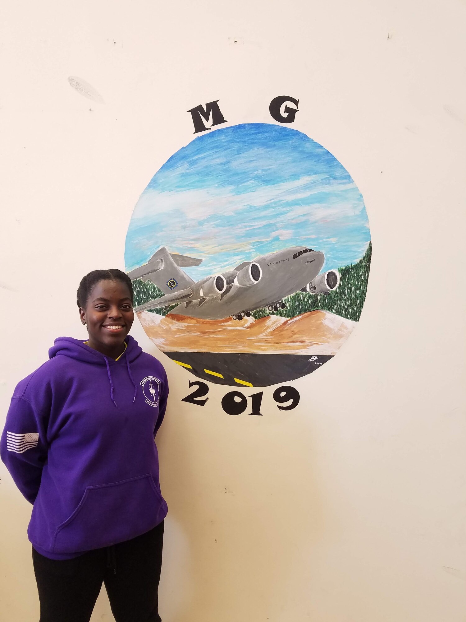 U.S. Air Force Airman 1st Class Briana Antoine-Bazan, an air terminal operations center information controller, stands in front of her art piece at Fairchild Air Force Base, Washington, Oct. 1, 2019.