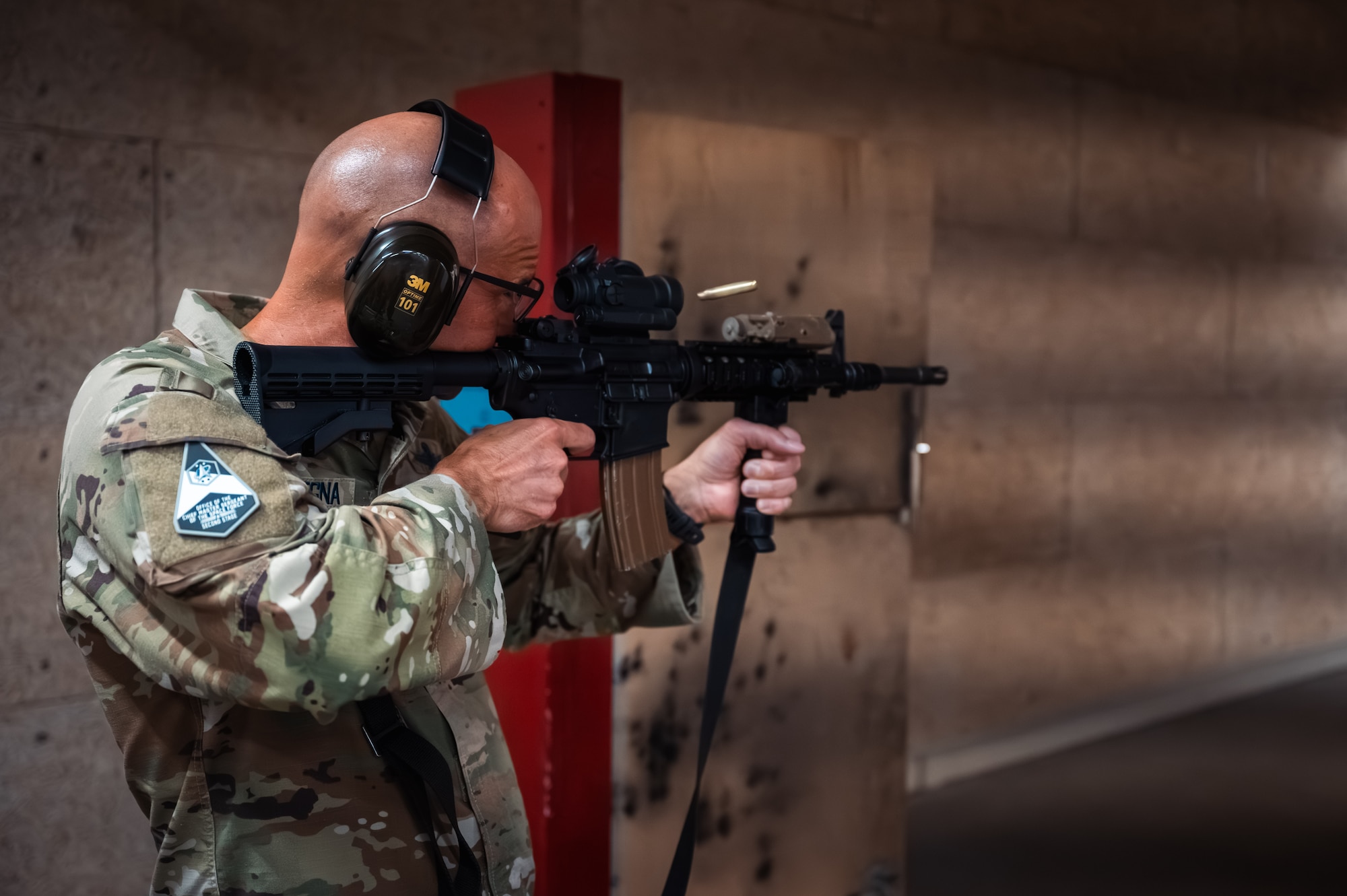 man aims rifle down a firing range