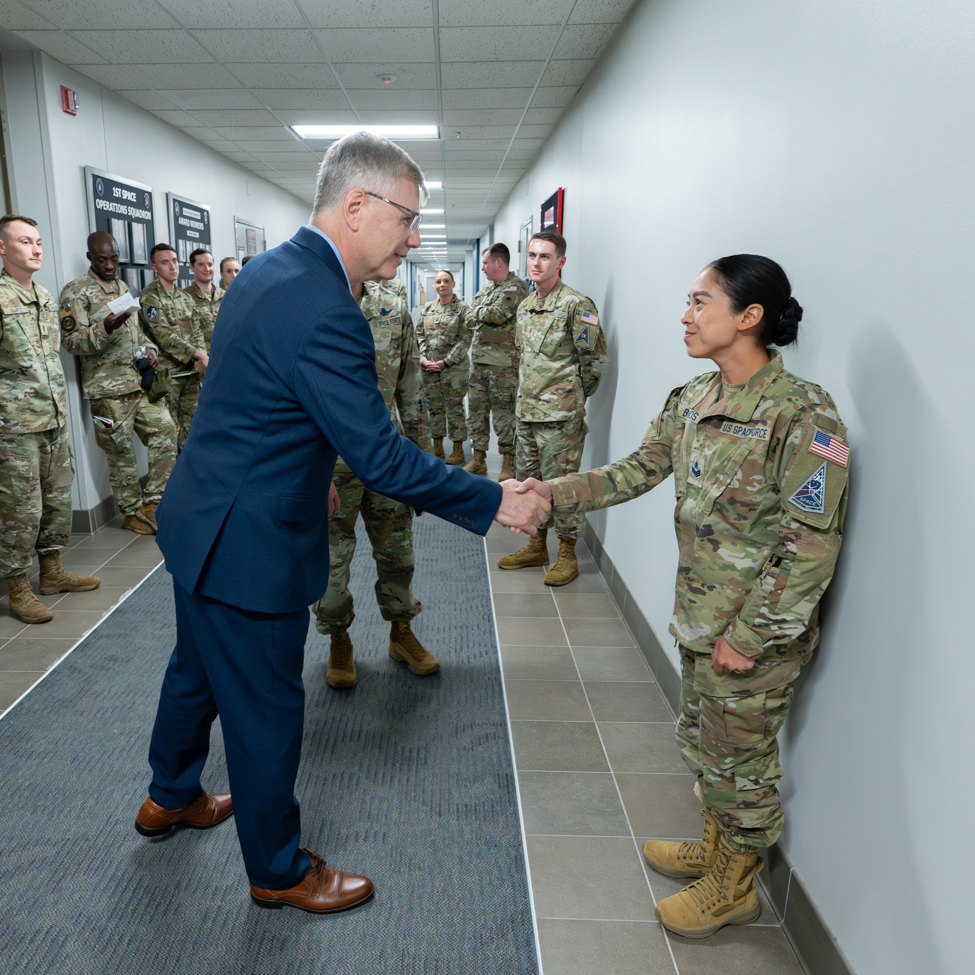 Secretary of the Air Force Troy Meink presents a challenge coin to U.S. Space Force Sgt. Catherine Bolanos of Space Delta 9 (Orbital Warfare) at Schriever Space Force Base, Colorado, May 28, 2025. Space Operations Command Guardians and Airmen demonstrated their combat readiness and warrior ethos, providing Meink with a deep dive into multiple critical mission areas, to include Space Domain Awareness; Electromagnetic Warfare; Missile Warning; Intelligence, Surveillance, Reconnaissance and Targeting; Orbital Warfare and Positioning, Navigation and Timing; as well as the critical mission support provided by the U.S. Air Force.  (U.S. Space Force photo by Dave Grim)