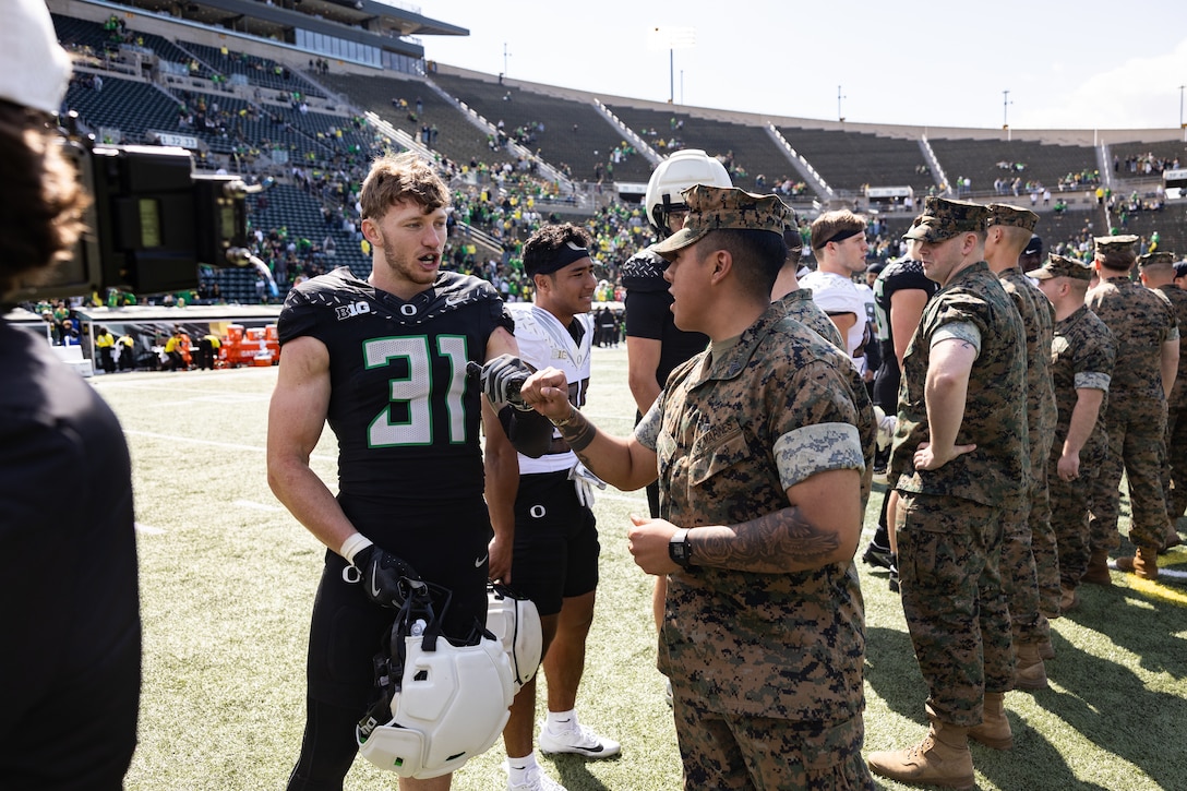 U.S. Marine Corps Sgt. Jose Marin, a canvassing recruiter with Recruiting Sub-Station Eugene, Recruiting Station Portland, interacts with Dillon Thieneman, a University of Oregon football player, at the conclusion of the University of Oregon Spring football game in Eugene, Oregon, April 26, 2025. The Spring game had military involvement which included an F-15 Eagle flyover, veteran recognitions, a reenlistment and promotion ceremony, and a post-game gift exchange between the Oregon football team and service members. (U.S. Marine Corps photo by Sgt. Andrew Bray)