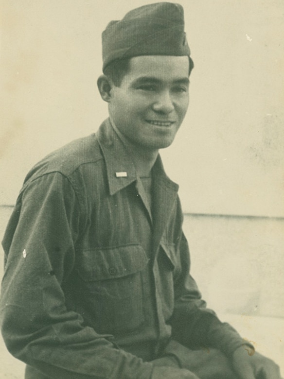 A seated man in a military uniform smiles.