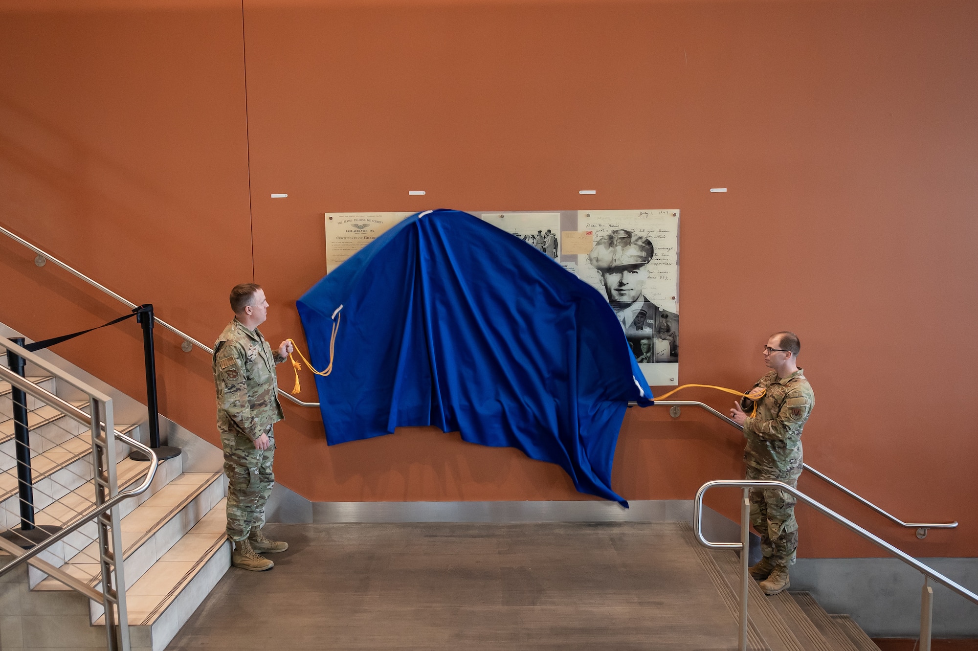 Two men unveil panel.