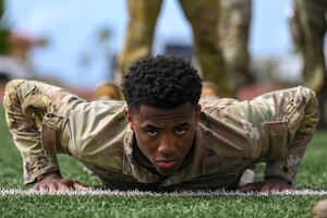 Photo of an Airman preparing to do push-ups during an advanced combat skills assessment