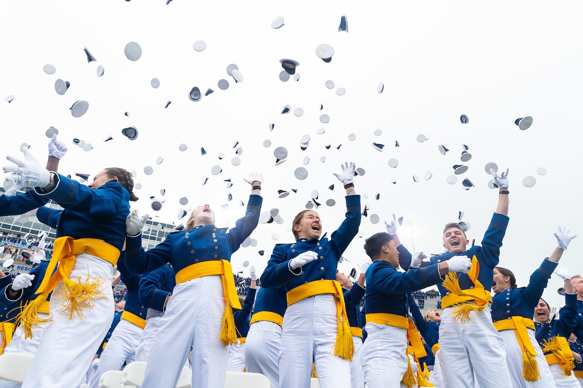 Dozens of graduates toss their caps.