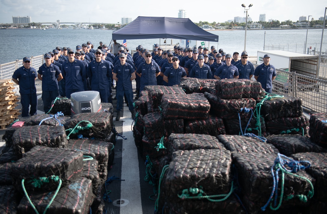The crew of USCGC Thetis (WMEC 910) poses for a group photo behind more than 28,500 pounds of seized drugs.
