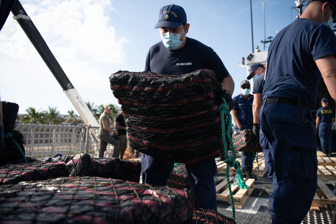 A USCGC Thetis crew member stacks a bale of cocaine on a pallet during a drug offload at Port Everglades.