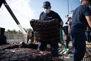 A USCGC Thetis crew member stacks a bale of cocaine on a pallet during a drug offload at Port Everglades.