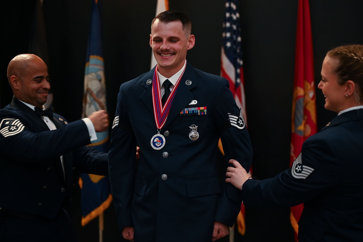 U.S. Air Force Senior Airman Joseph Orcutt, 17th Security Forces Squadron emergency communications controller, pins on the rank of staff sergeant placed on his arms by Tech. Sgt. Madyson Grace Lavender, 17th SFS flight chief, and Master Sgt. Darren Ortiz, 17th SFS first sergeant, during the ALS Class 25-D graduation at the Powell Event Center, Goodfellow Air Force Base, Texas, May 22, 2025. After graduating from ALS, airmen are eligible for promotion to staff sergeant. (U.S. Air Force photo by Senior Airman Evelyn J. D’Errico)