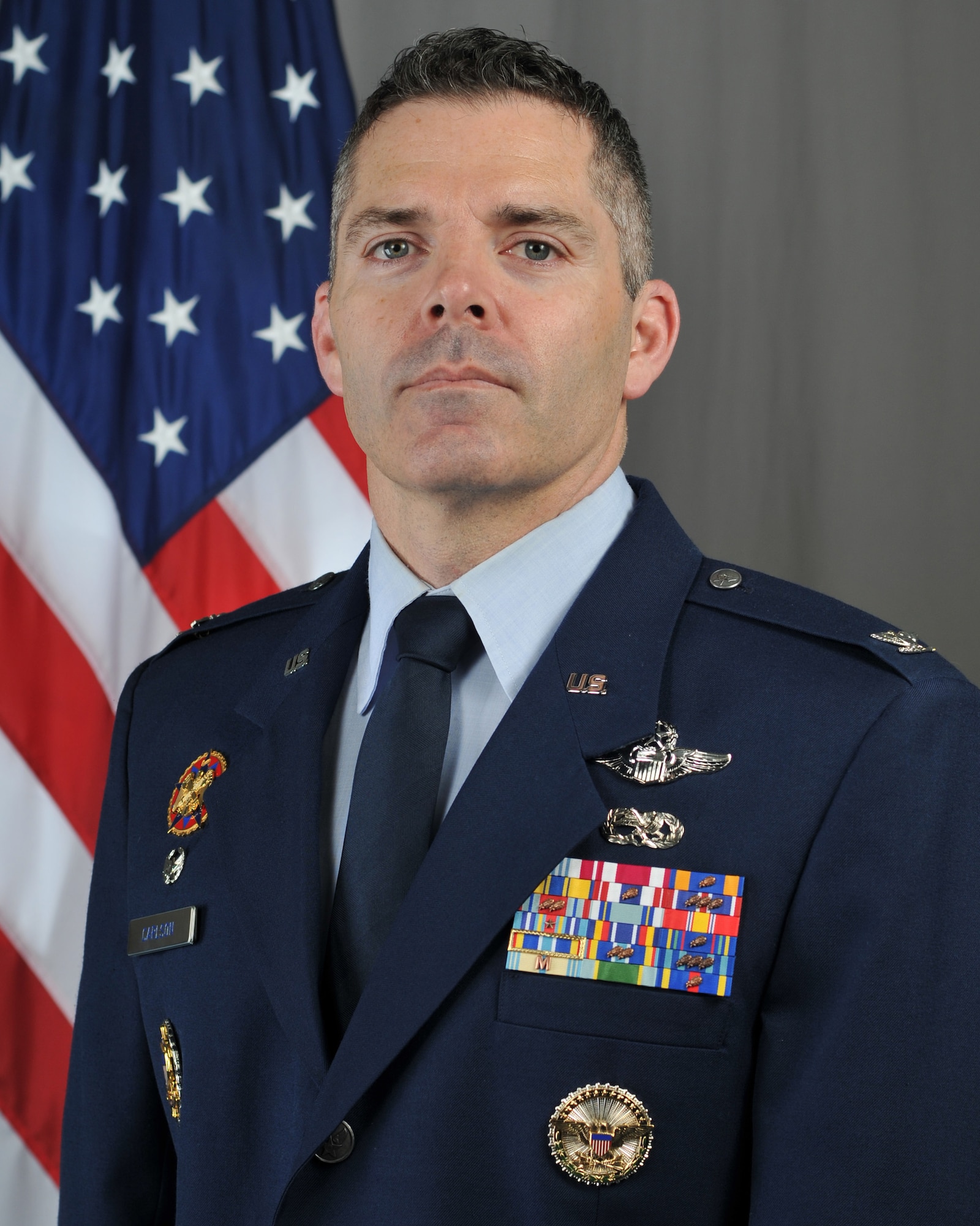 U.S. Air National Guard Col. Adam Carlson, incoming 185th Air Refueling Wing Commander, stands in front of an American flag