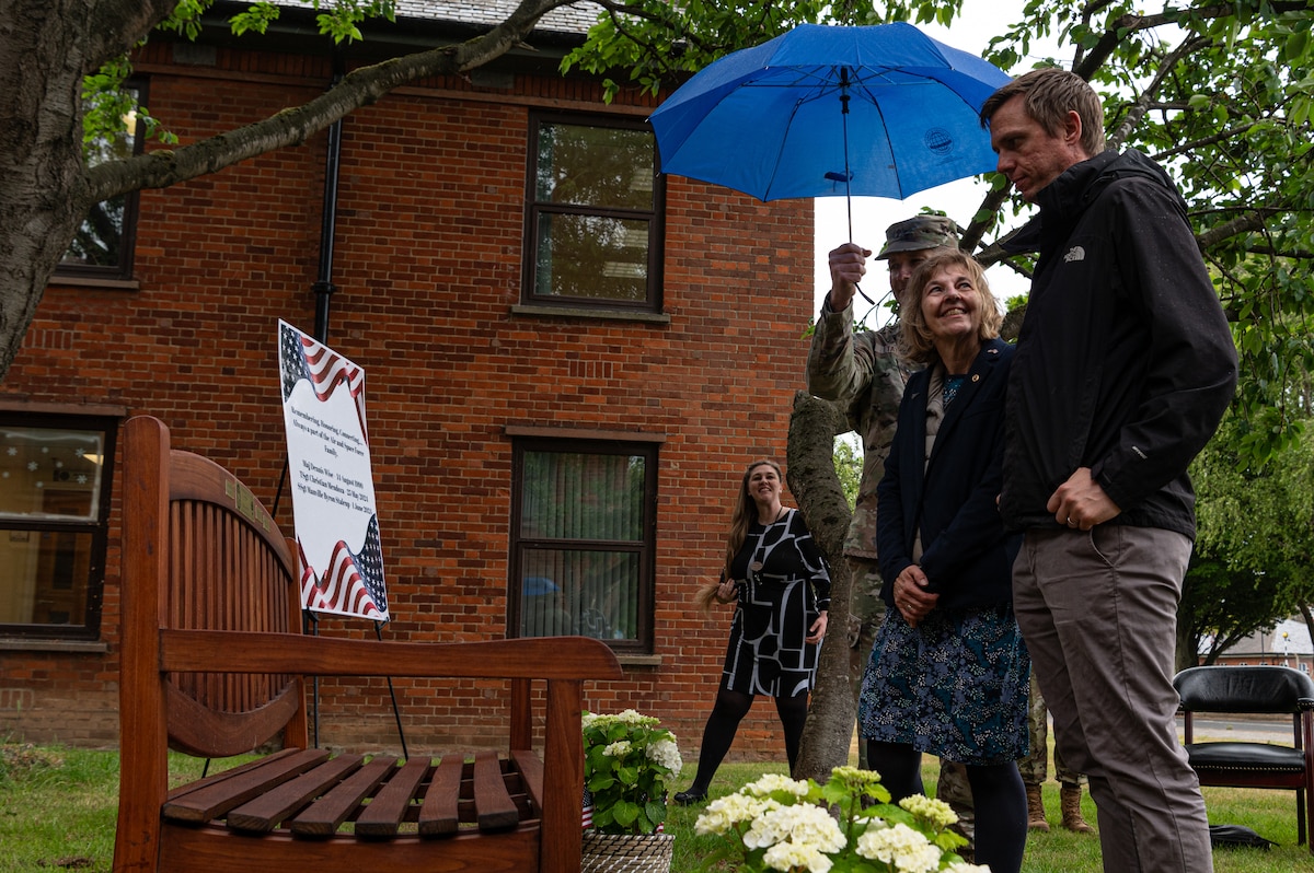 David Wise, right, and Tessa Wise, center, son and wife of the late Royal Air Force Tornado pilot Maj. Dennis Wise, stand by the unveiled bench honoring fallen service members of Team Mildenhall during the Air Force Families Forever memorial ceremony at RAF Mildenhall, England, May 27, 2025.