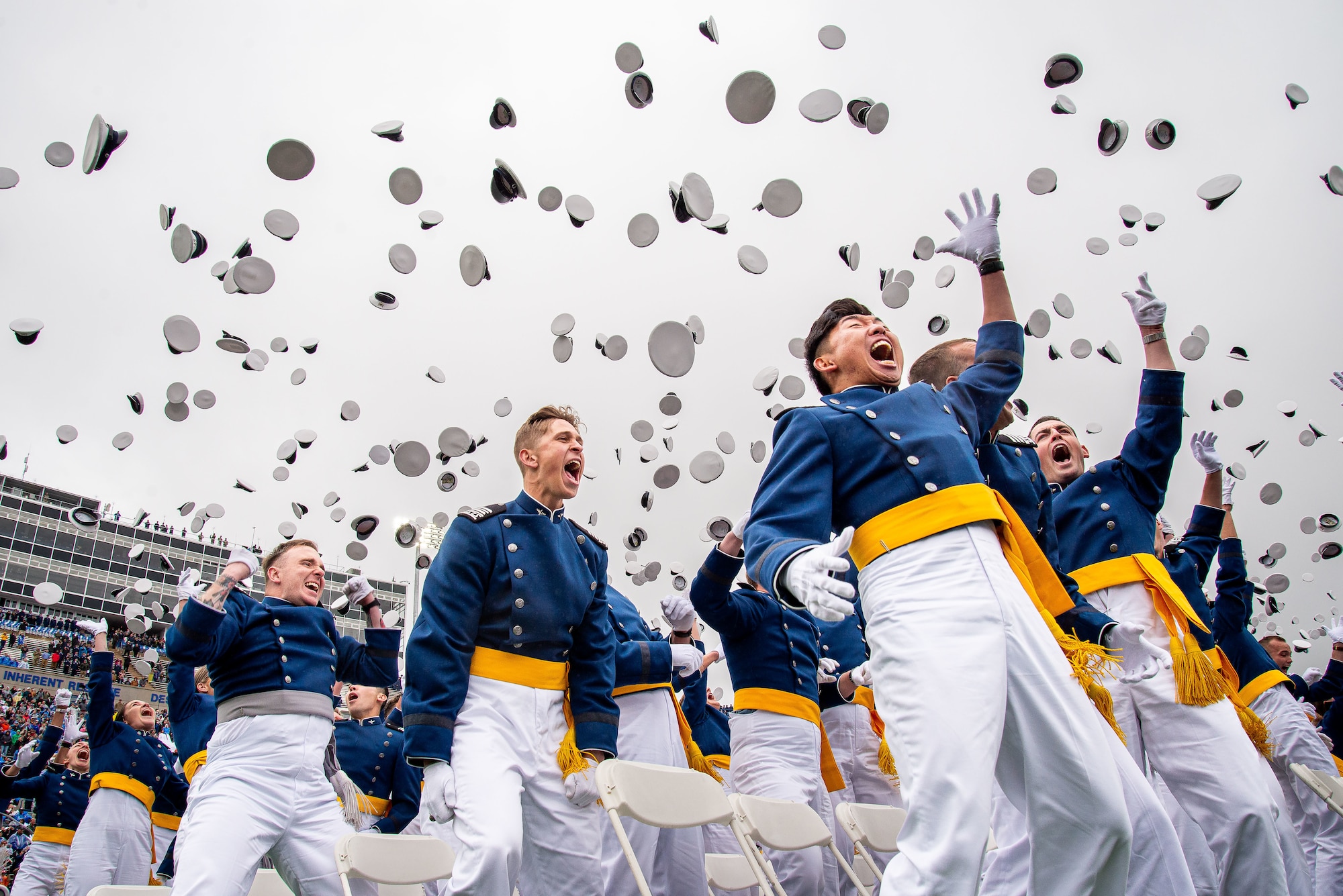 photo of cadets cheering while their white hats fly in the air
