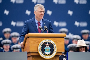 Secretary of the Air Force Troy Meink stands at a podium on stage and speaks to the graduation attendees