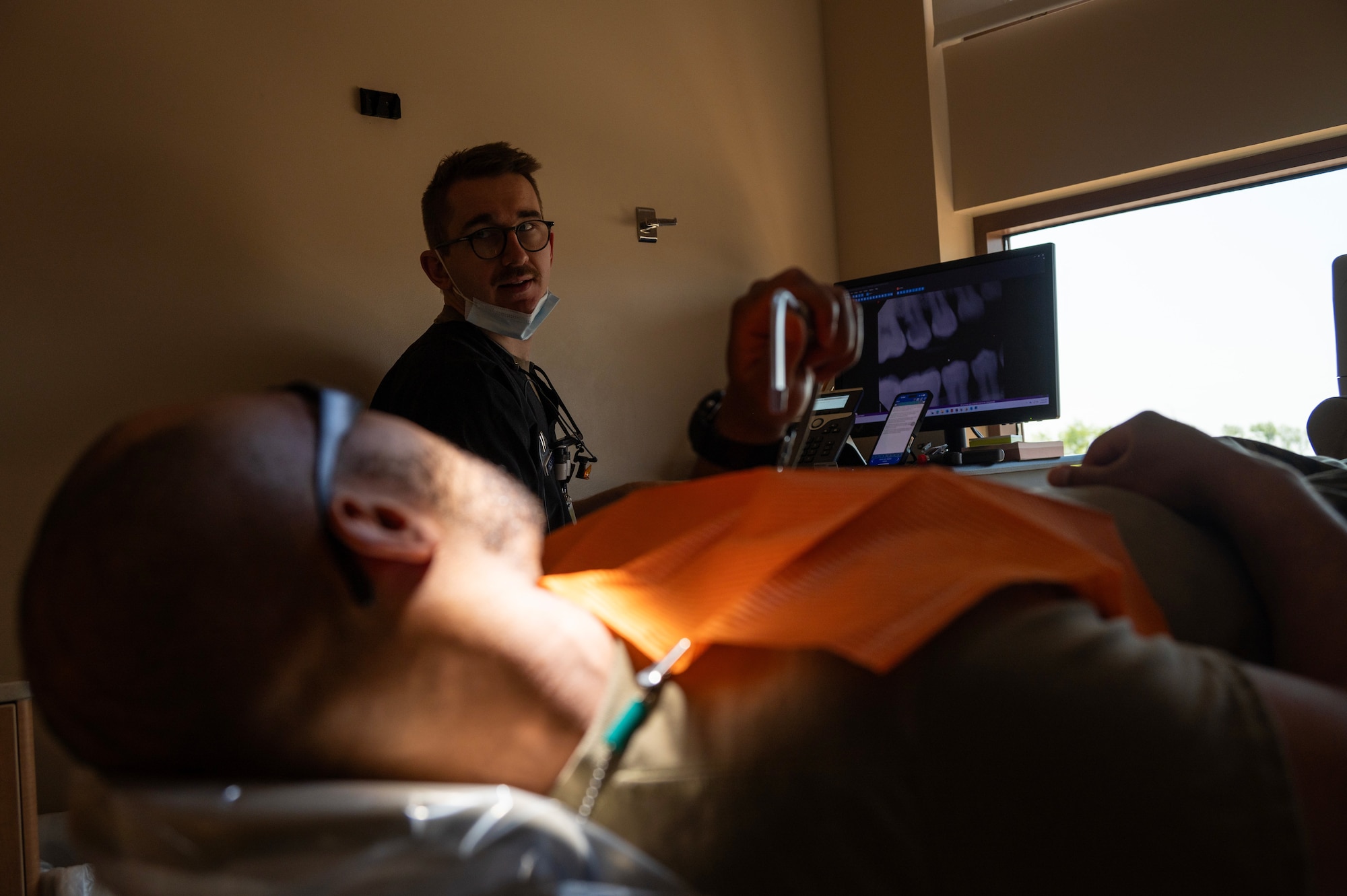 U.S. Air Force Capt. Phillip Sheridan, 5th Operational Medical Readiness Squadron (OMRS) general dentist, discusses X-ray results with a patient at Minot Air Force Base, North Dakota, May 28, 2025. To keep Airmen mission-ready, the 5OMRS dental flight works to provide service members with the best possible care. (U.S. Air Force photo by Senior Airman Alyssa Bankston)