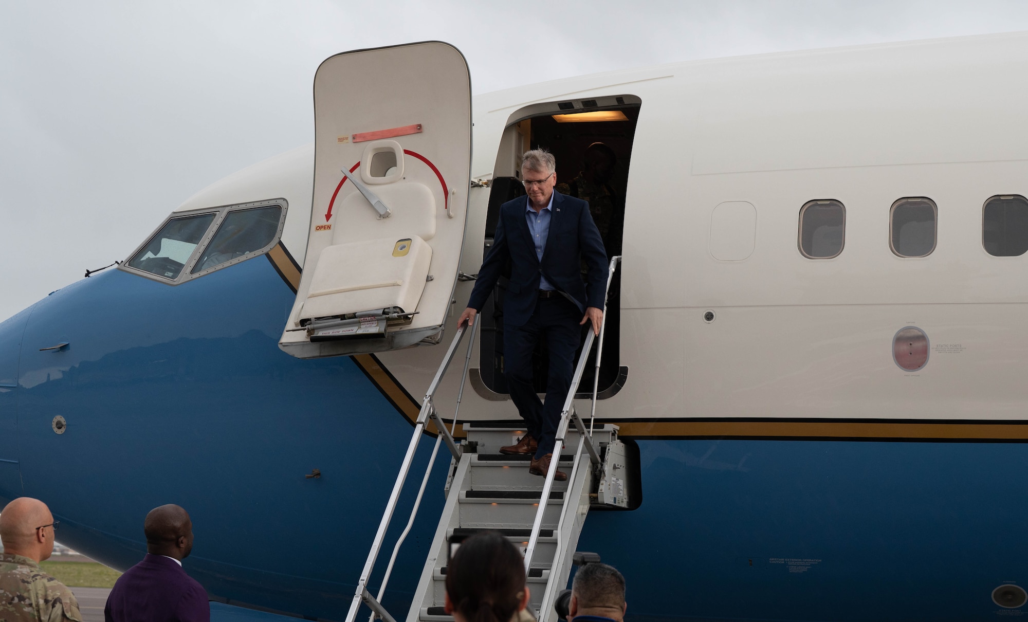 Secretary of the Air Force Troy Meink exits an airplane down a flight of stairs.