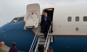 Secretary of the Air Force Troy Meink exits an airplane down a flight of stairs.