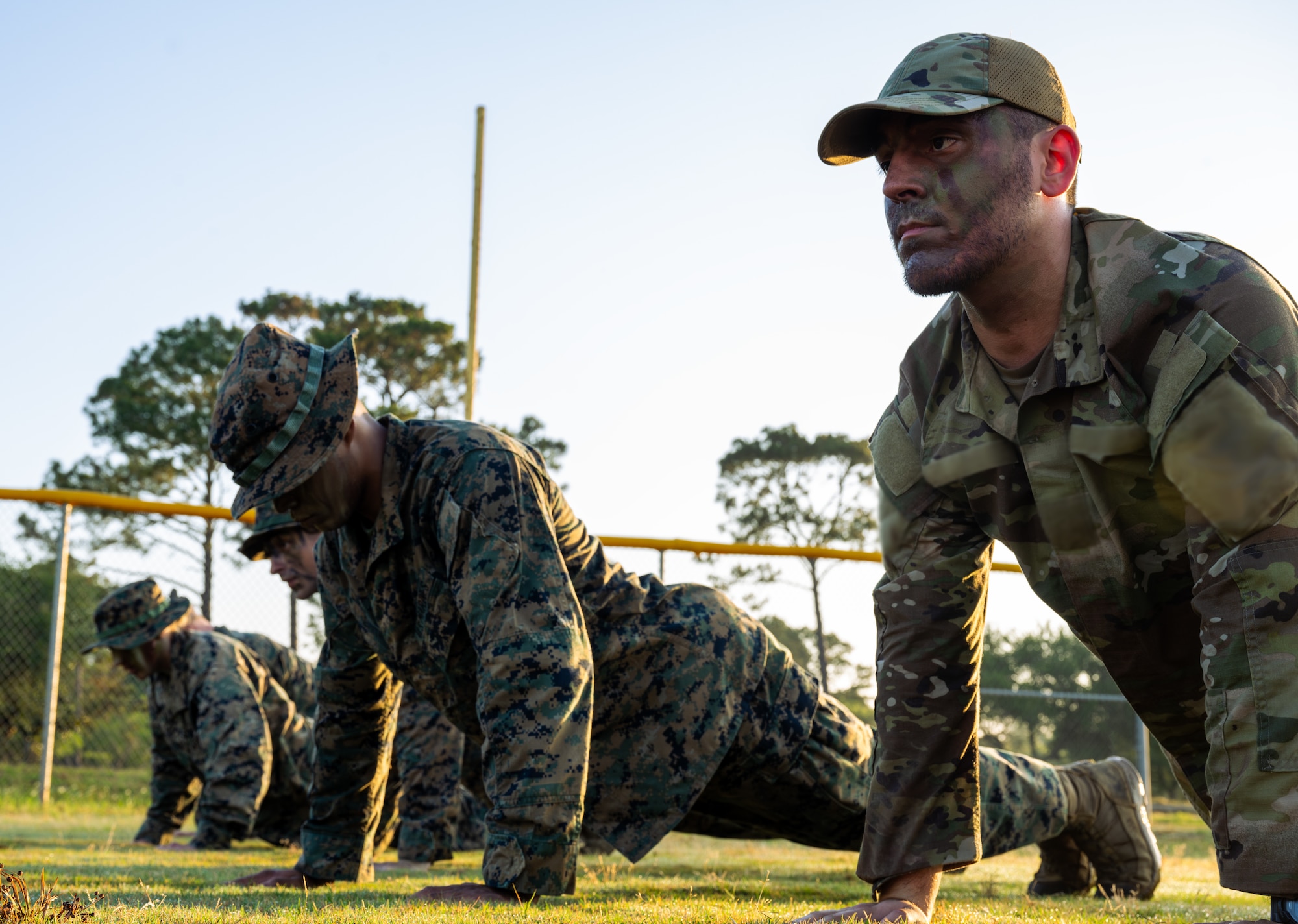 U.S. Marines and an Airman, right, assigned to the 1st Special Operations Wing, do push-ups during Corporals Course.