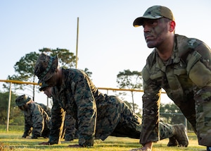 U.S. Marines and an Airman, right, assigned to the 1st Special Operations Wing, do push-ups during Corporals Course.