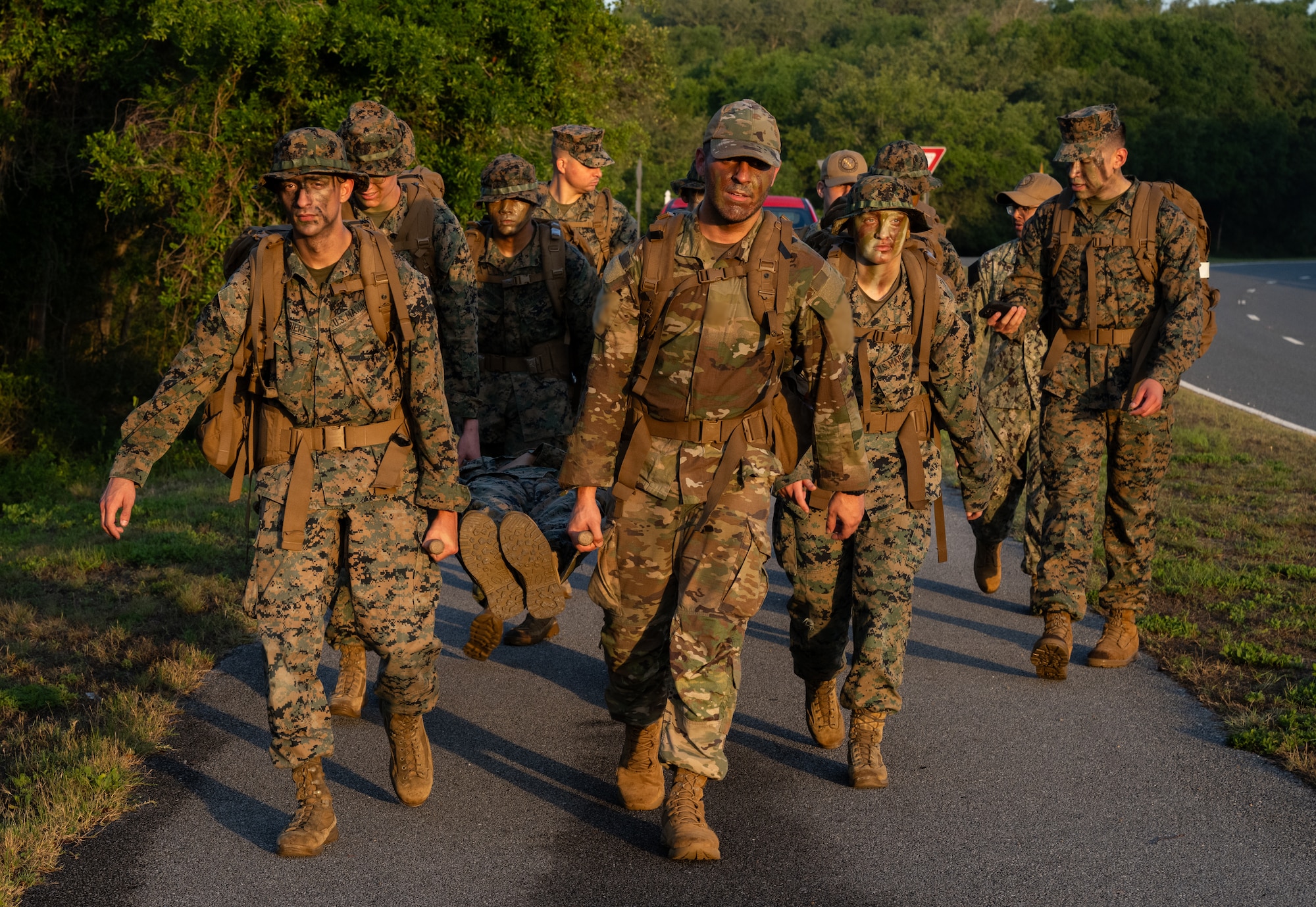 U.S. Marines and an Airman carry a mock casualty during a ruck march.