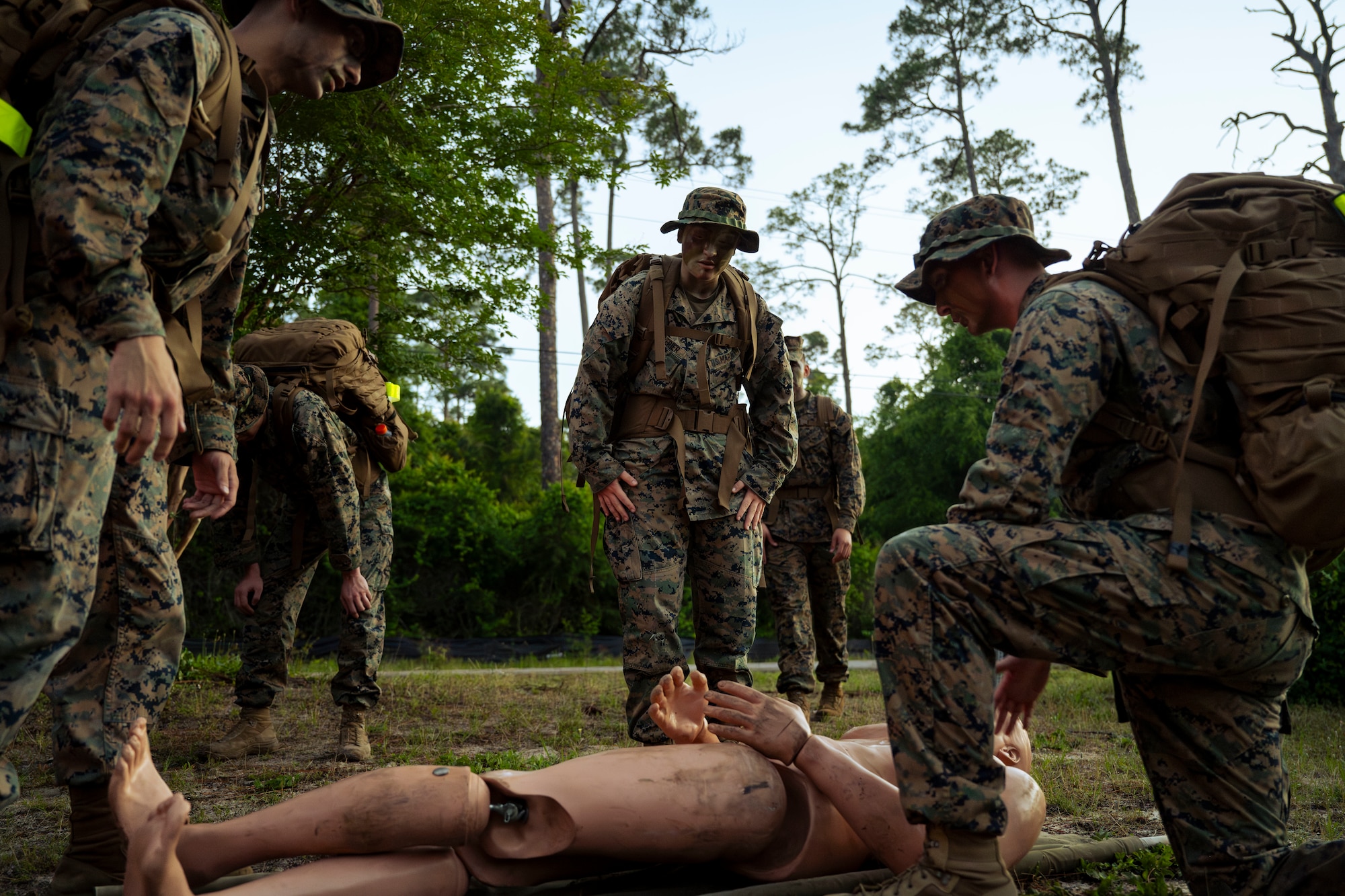 Three U.S. Marines gather around a mock casualty dummy.