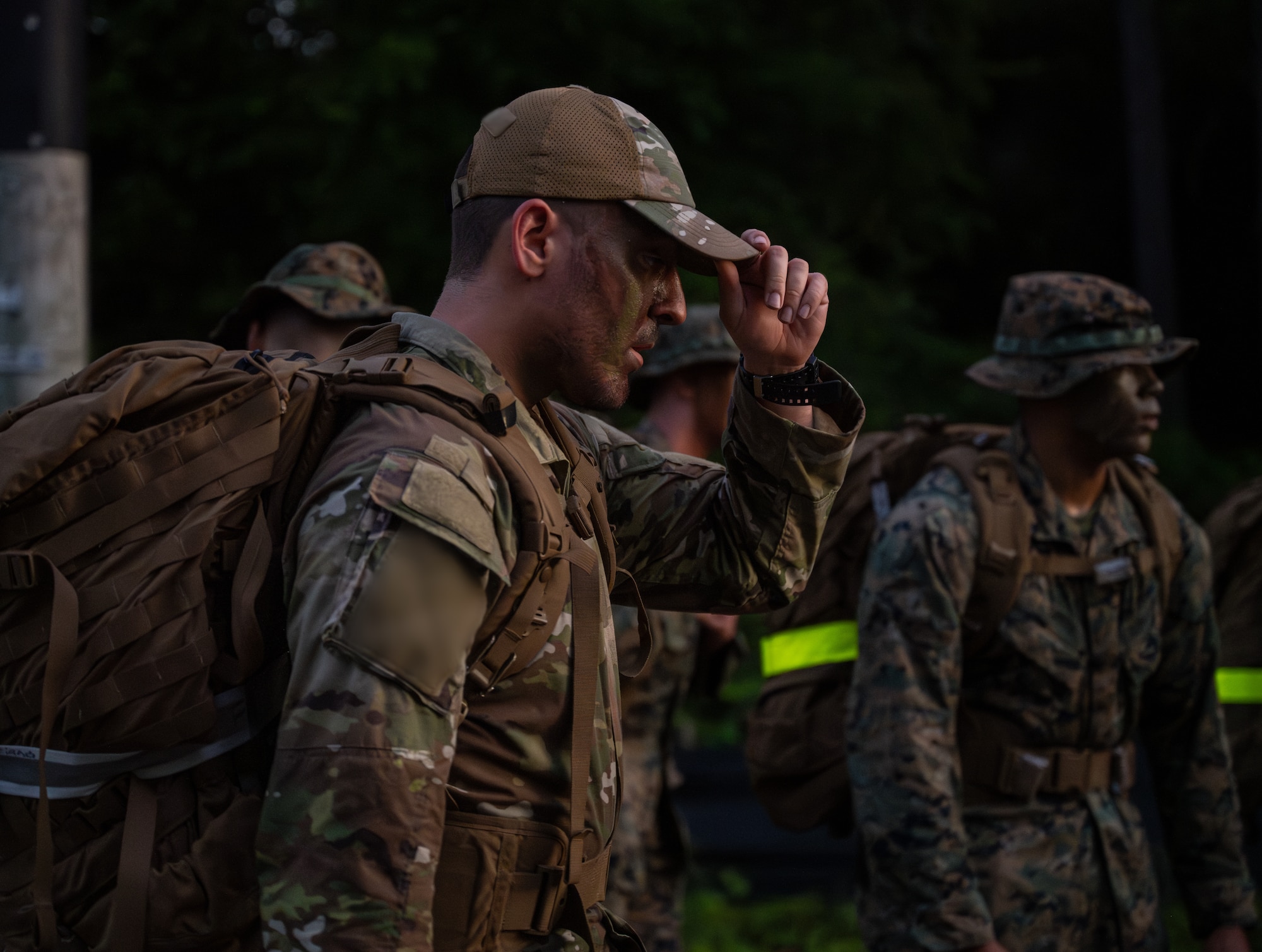 An Airman is centered, adjusting his cap.
