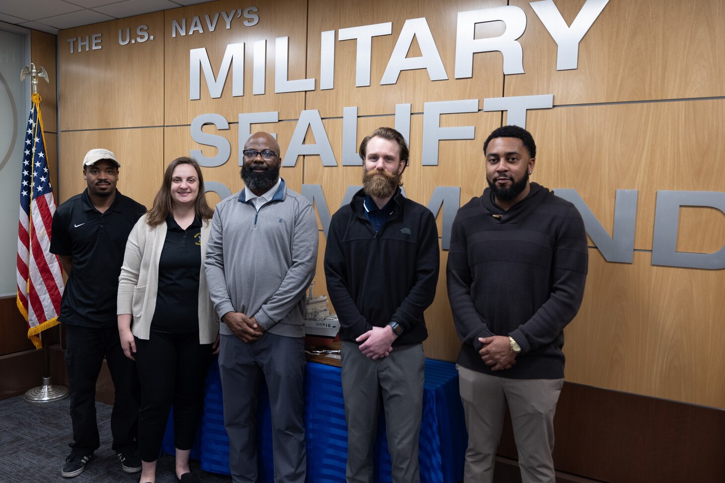 Military Sealift Command's Transportation Team pose for a photo. From Left to right: Marcus Williams (Transportation Assistant), Carly Tew (Transportation Officer), Carlos Douglas (Lead Transportation Officer), Zachary Farr (Transportation Officer), and Antwan Epps (Transportation Assistant). The team transports vital material and parts to more than 140 MSC ships