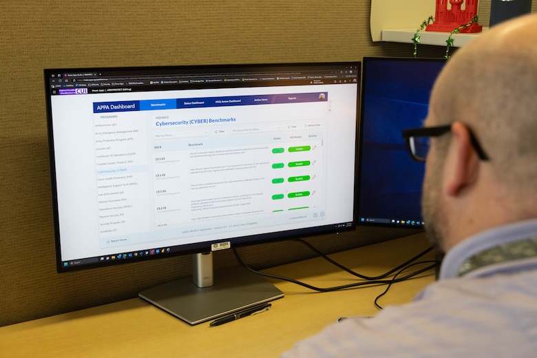 A man in a purple shirt looks at a white computer screen with green text boxes on the right hand side.