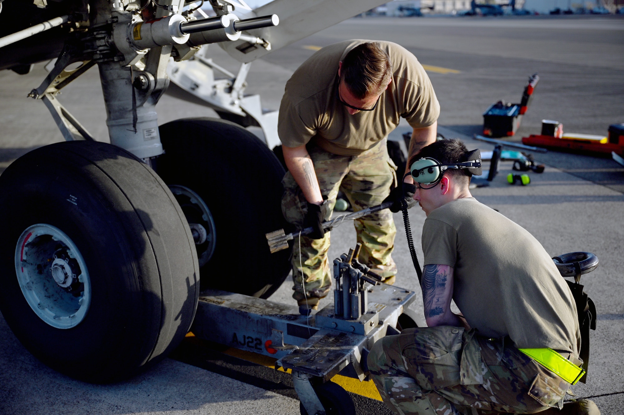 U.S. Air Force Tech. Sgt. Mark Tornetta, left, 445th Maintenance Squadron avionics technician, and Senior Airman Marcus Simones, right, 445th Aircraft Maintenance Squadron aerospace ground equipment airframe powerplant general, use a tire jack on nose landing gear to replace tires on a C-17 Globemaster III aircraft at Yokota Air Base, Japan, April 14, 2025. The landing gear was identified as beyond limits during the thru-flight inspection. (U.S. Air Force photo by Staff Sgt. Johnathan Quiñones)
