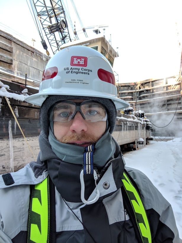 Man in hardhat stands in front of lock chamber on a snowy day