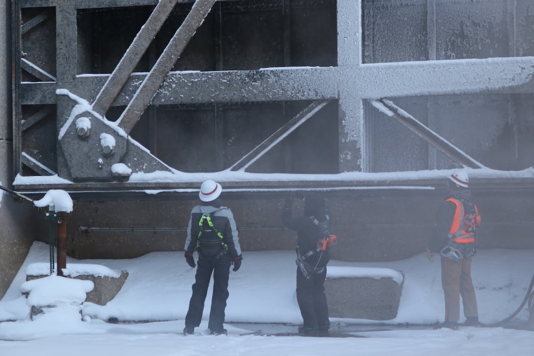 Man in hardhat stands in front of lock chamber on a snowy day