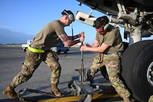 U.S. Air Force Senior Airman Marcus Simones, left, 445th Aircraft Maintenance Squadron aerospace ground equipment airframe powerplant general, and Master Sgt. John McDermott, right, 445th Maintenance Squadron jet mechanic, use a tire jack on nose landing gear to replace tires on a C-17 Globemaster III aircraft at Yokota Air Base, Japan, April 14, 2025. The landing gear was identified as beyond limits during the thru-flight inspection. (U.S. Air Force photo by Staff Sgt. Johnathan Quiñones)
