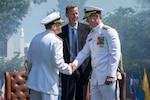 Rear Adm. Tom Anderson salutes sideboys alongside his wife during his retirement ceremony held at the Washington Navy Yard’s Leutze Park, May 30.