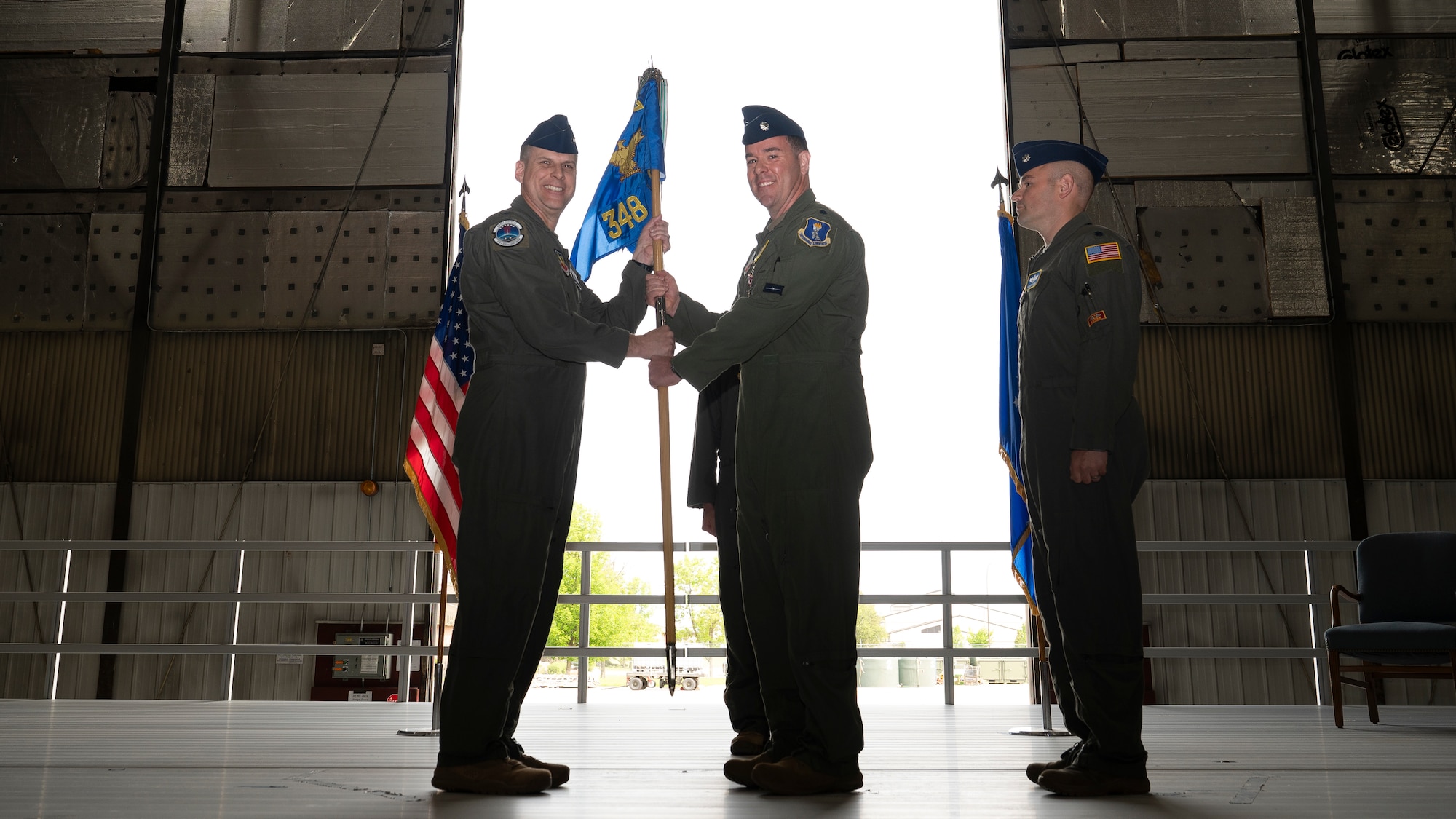 Col. Eric Steele, 319th Operations Group commander, accepts the 348th Reconnaissance Squadron guidon from Lt. Col. Cory Turner, 348th RS outgoing commander, during the 348th RS change of command ceremony at Grand Forks Air Force Base, N.D., May 30, 2025. The passing of the guidon from the outgoing commander to the presiding official symbolizes the relinquishment of command. (U.S. Air Force photo by Airman Nailah Pacheco)