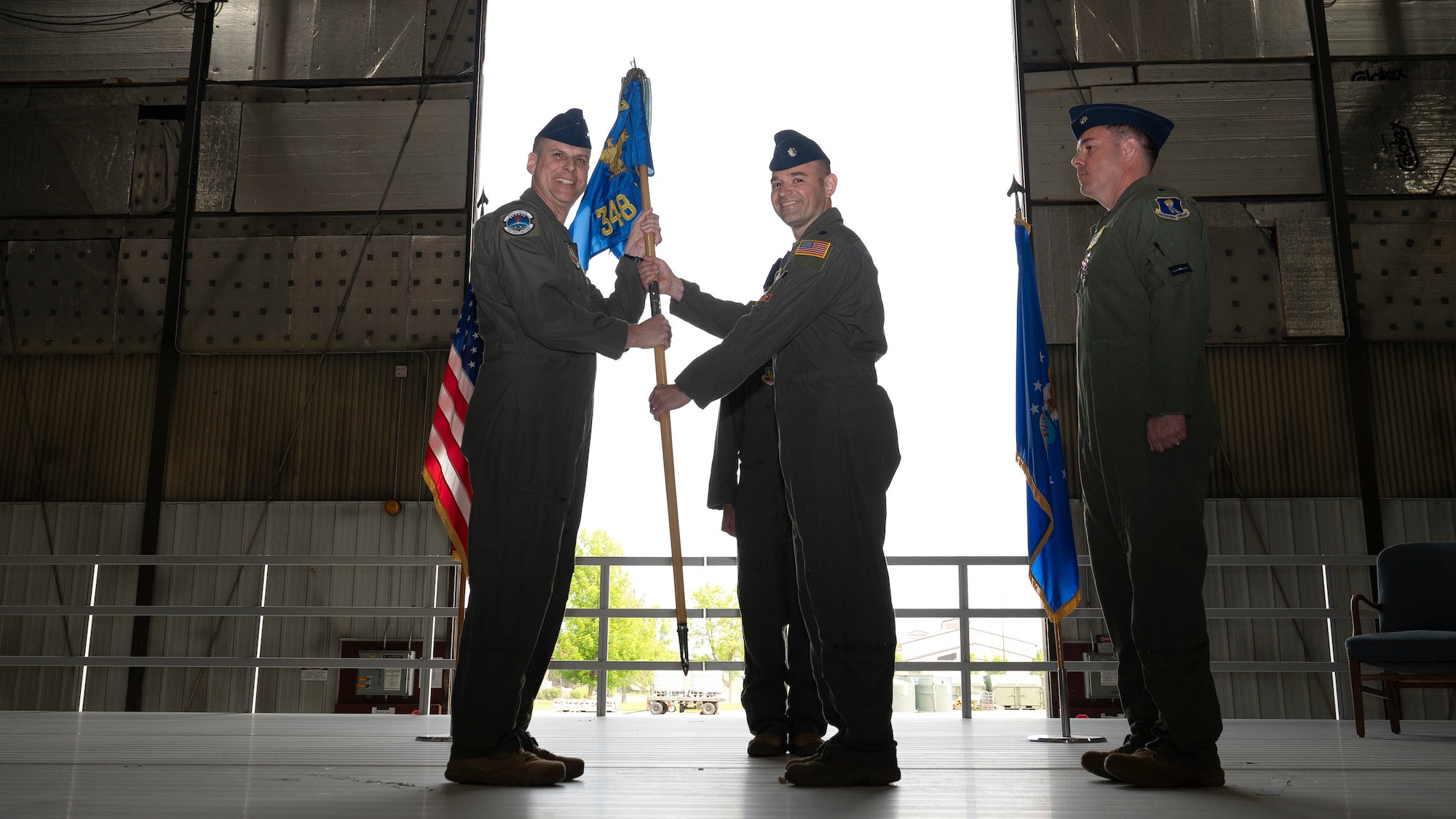 Col. Eric Steele, 319th Operations Group commander, passes the 348th Reconnaissance Squadron guidon to Lt. Col. Robert Damron, 348th RS incoming commander, during the 348th RS change of command ceremony at Grand Forks Air Force Base, N.D., May 30, 2025. The passing of the guidon to the incoming commander symbolizes the acceptance of command. (U.S. Air Force photo by Airman Nailah Pacheco)