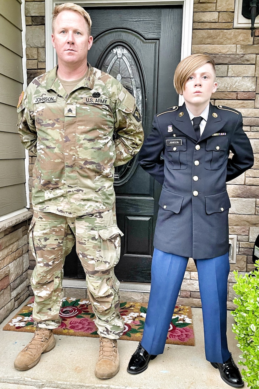A man and a teen stand at ease on a patio. Both wear uniforms.