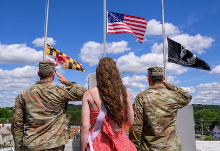 Two soldiers and a young woman salute a flag