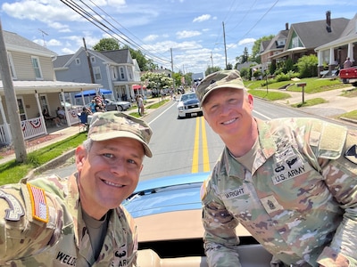 Two soldiers riding in a convertible vehicle for a parade