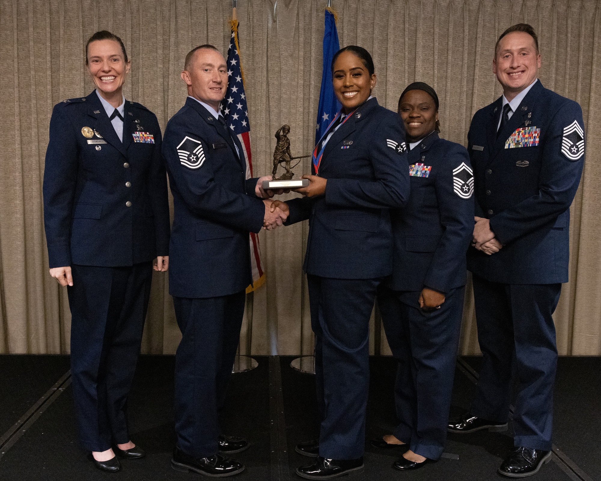 Airman receives an award in front of the American flag