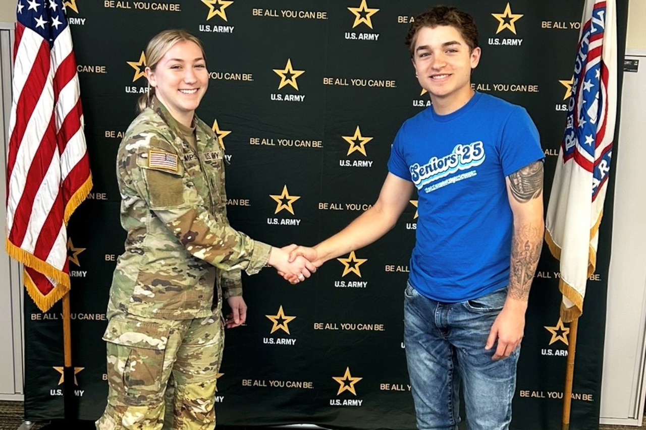A person in uniform shakes the hand of a teen.