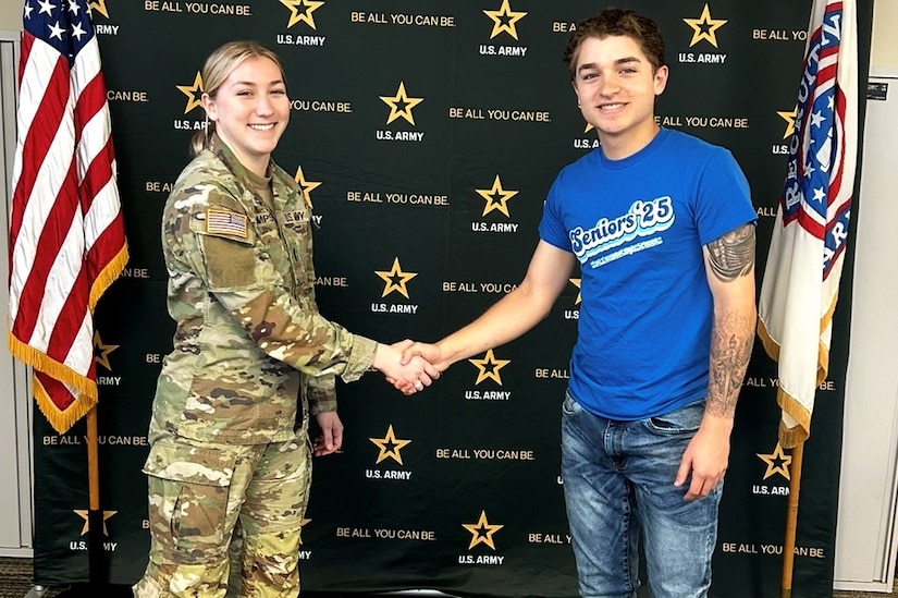 A person in uniform shakes the hand of a teen.