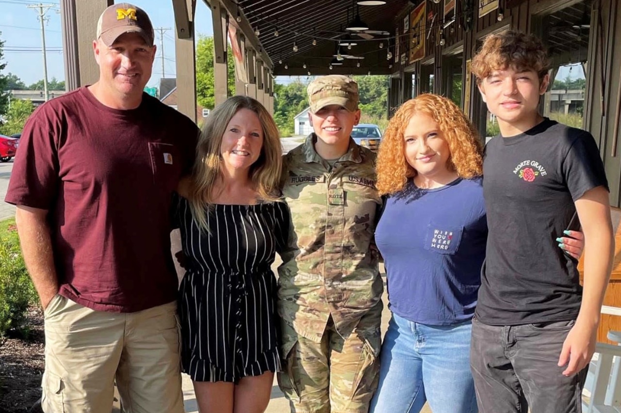 A family of five poses for a photo outdoors.