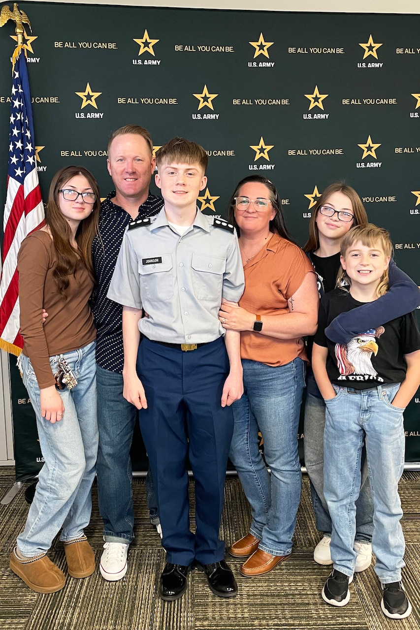 A family of six poses for a photo next to an American flag.