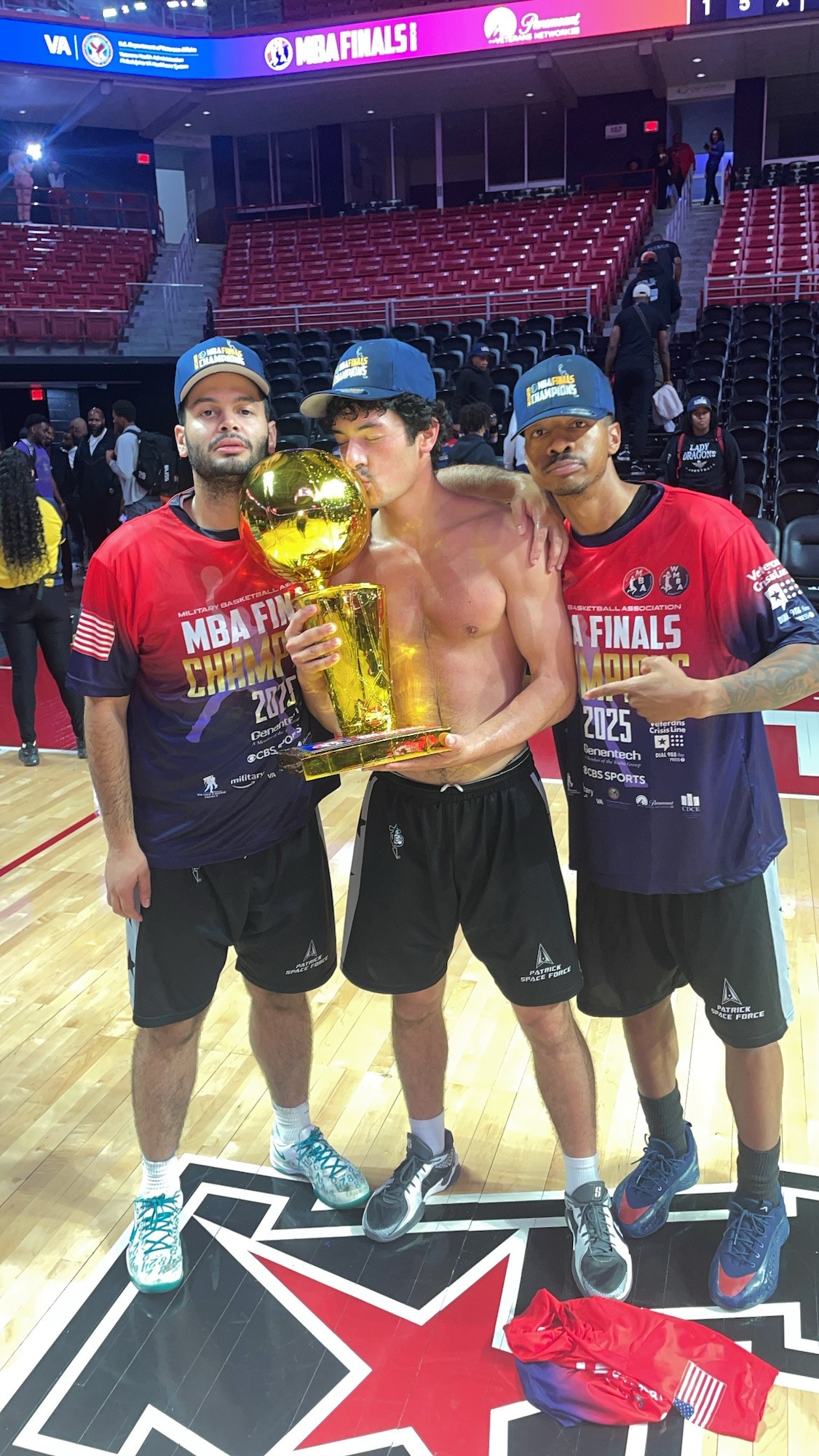 SrA Kareem Martin, Mr. Grayson Tejeda, and SrA Marcel Odom, members of the Patrick Space Force Base Varsity Basketball Team, celebrate with the championship trophy after defeating Fort Bliss 87-78 at the 2025 Military Basketball Association Finals in Philadelphia, Pennsylvania on May 25, 2025.