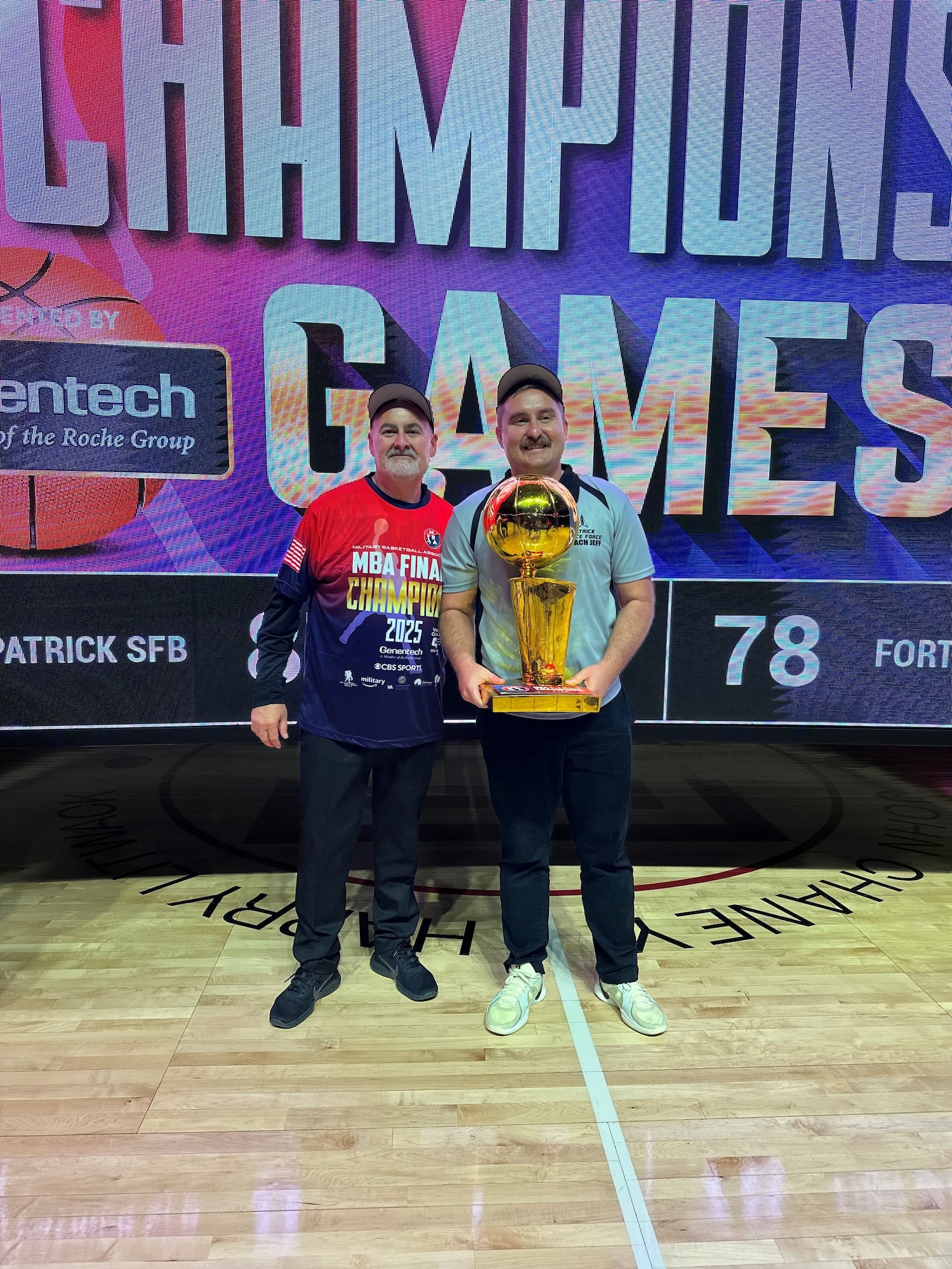 Space Launch Delta 45 coaches, Mr. Matthew Hurst and SSgt Jeffrey Hunt pose with the Military Basketball Association Championship trophy in Philadelphia, Pennsylvania on May 25, 2025. The photo opportunity followed their 87-78 victory over Fort Bliss in the final game of the 2025 DoD Varsity Basketball Tournament.